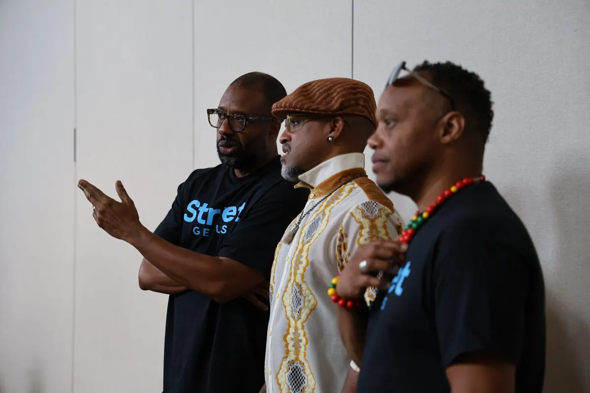 Bavu Blakes gestures while speaking with two collaborators at a Street Genius gathering.